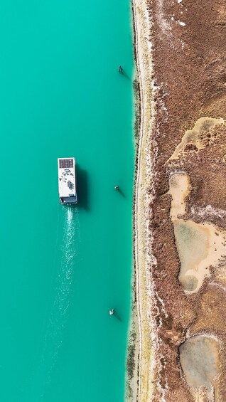 A boat anchored near a rocky shoreline with clear turquoise water. 1