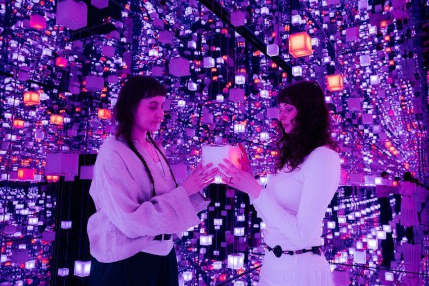 Two people exchanging a small object in a room filled with hanging lights. 4
