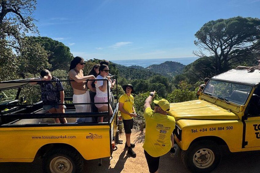 A group of people on a yellow vehicle with a scenic view of a forested landscape. 4