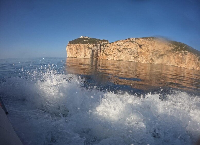 A large rock formation with a small building on top, surrounded by water. 4