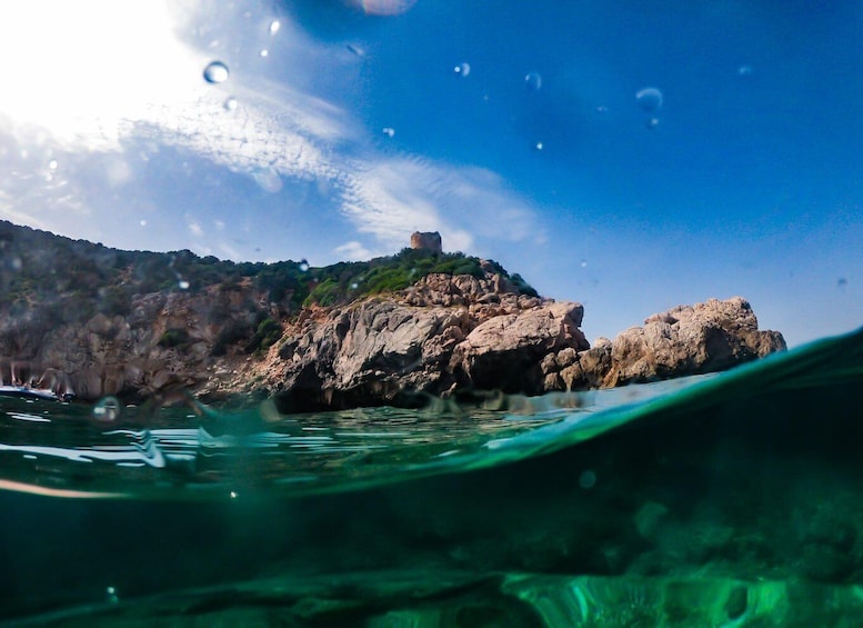 A coastal landscape with a rocky outcrop and a castle on top, viewed from underwater. 5