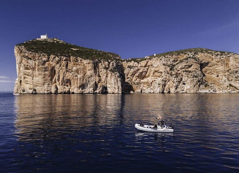 A boat on calm sea waters, cliffs with small buildings, and clear blue sky. 2