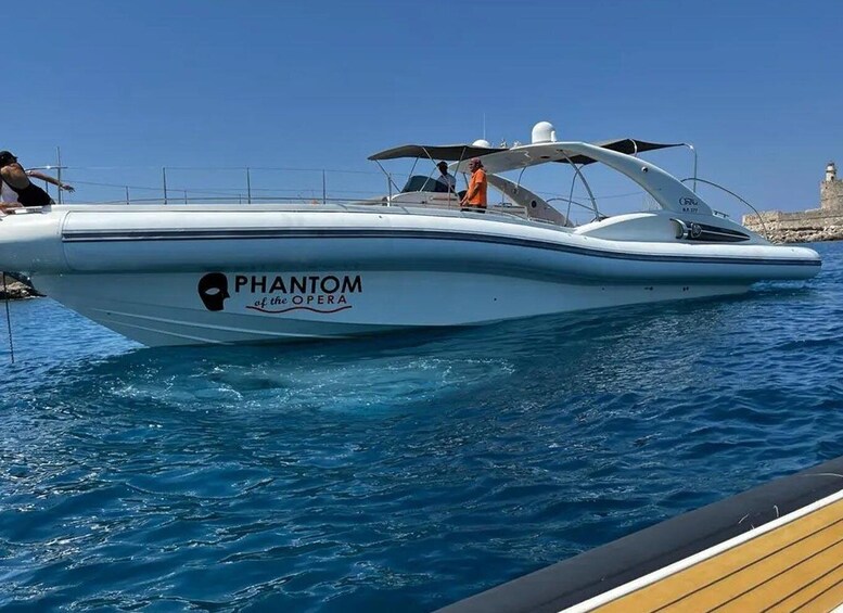 A white speedboat named 'PHANTOM of the OPERA' docked at a pier with clear blue water. 4
