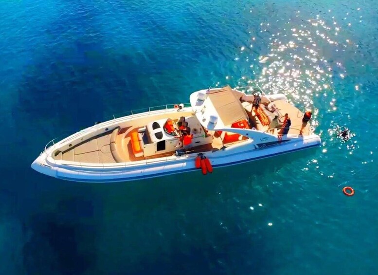 A white motorboat with a cabin and seating area, floating on clear blue water. 2