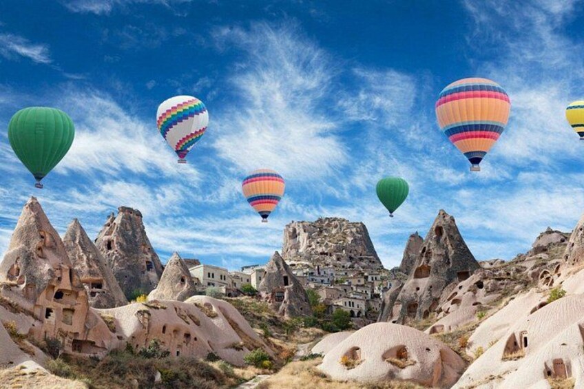 Hot air balloons, rock formations, and a town in Cappadocia. 1