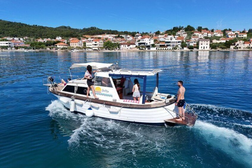 A boat with people on it, a wake behind it, and houses in the background. 3