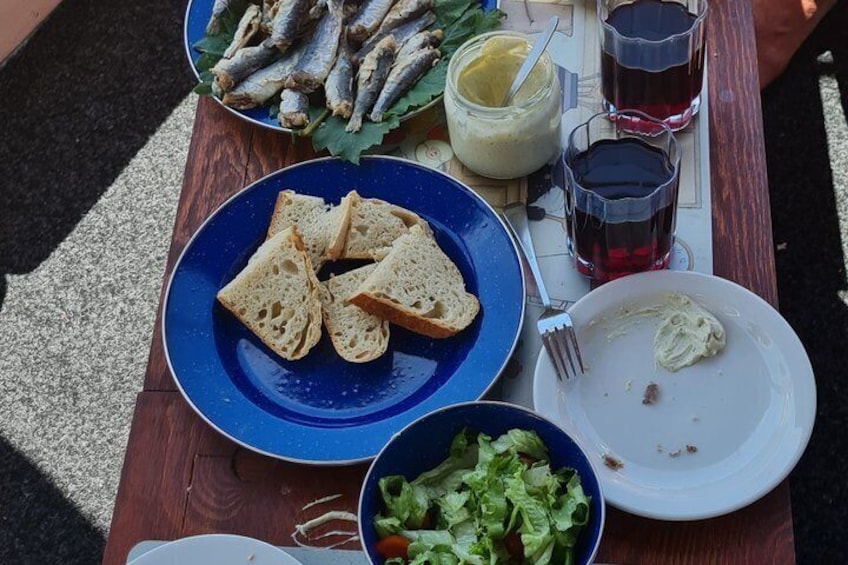 A picnic setup with bread, fish, salad, and drinks on a wooden table. 5