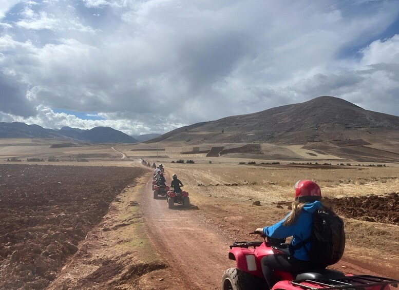 A group of people riding atv's on a dirt road through a mountainous landscape. 3