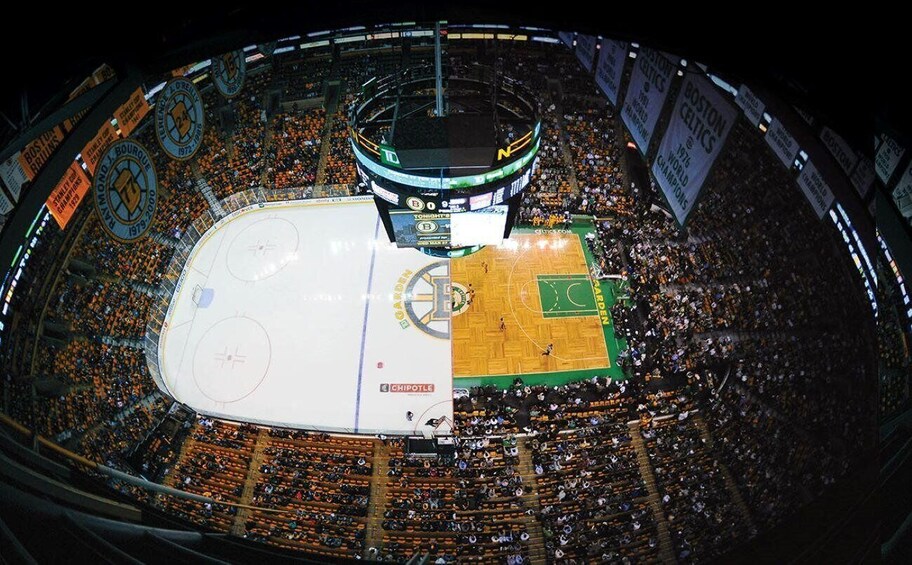 An indoor sports arena with multiple levels of seating, a central ice rink, and a basketball court. 2