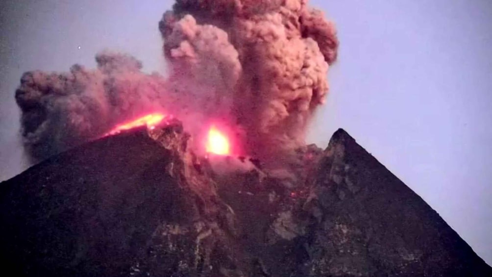 A volcano erupting with lava flowing down its sides. 4