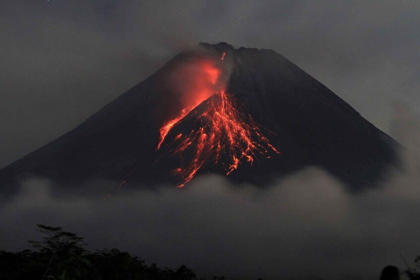 A volcano erupting at night with lava flowing down its side. 5