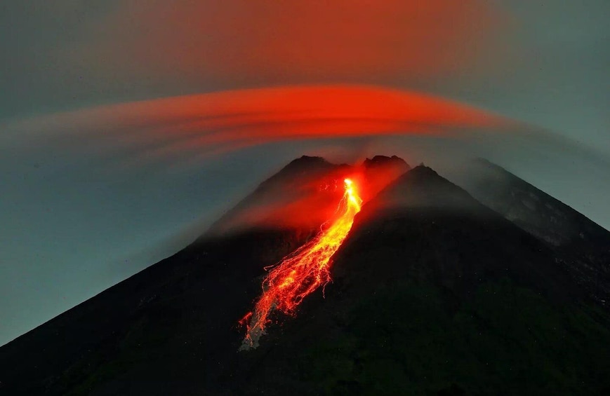 A volcano erupting with lava flowing down its side. 1