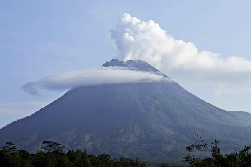 A volcano with a plume of smoke and clouds at its peak. 5