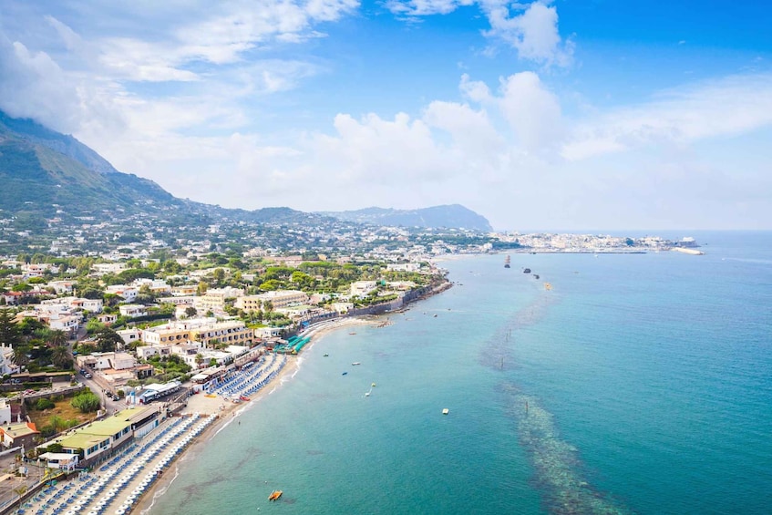 A coastal town with a beach, boats, and a mountain in the background. 5