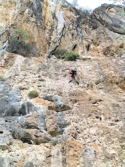 A person climbing a rocky mountain with sparse vegetation. 2