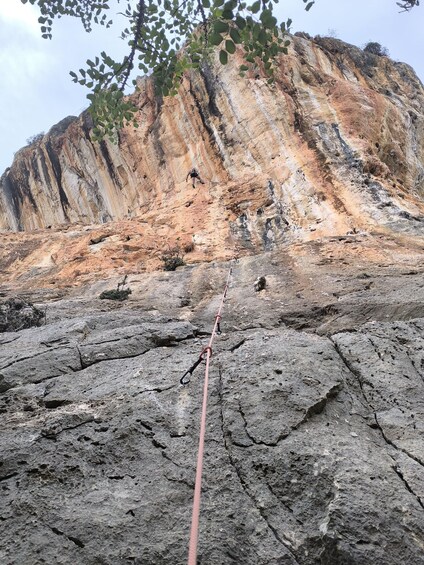 A rocky terrain with a climbing rope and a climber. 3