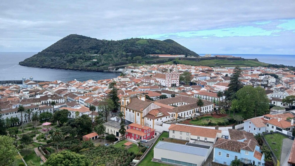 A coastal town with white buildings, a hill in the background, and a body of water. 4