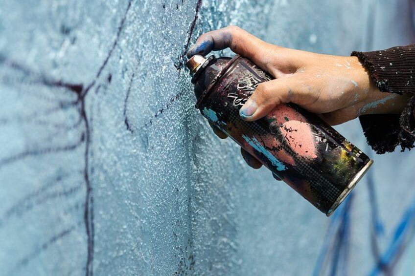 A hand holding a spray can applying paint to a wall. 2