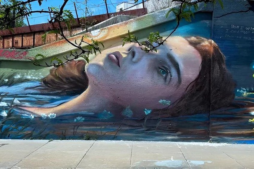 A mural of a person submerged in water with a bridge in the background. 1