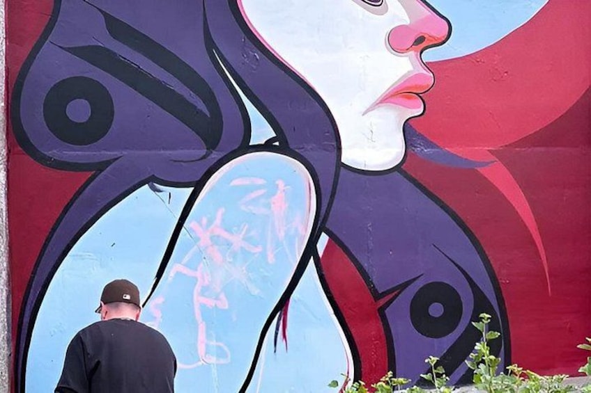 A mural with a woman's face and a man standing in front of it. 4