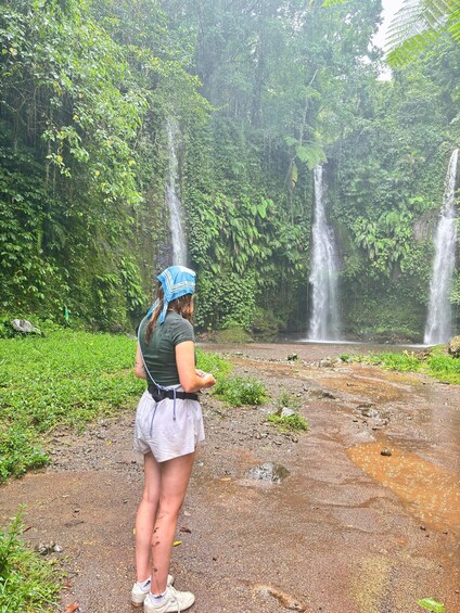 A woman standing by a waterfall in a lush forest. 5