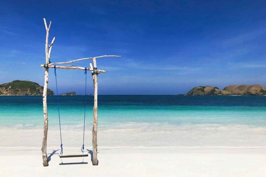 A beach with a wooden swing set and clear turquoise waters. 3