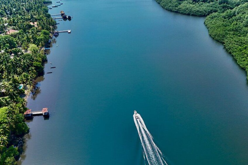 A boat speeding across a calm river, surrounded by lush greenery and docks along the banks. 4