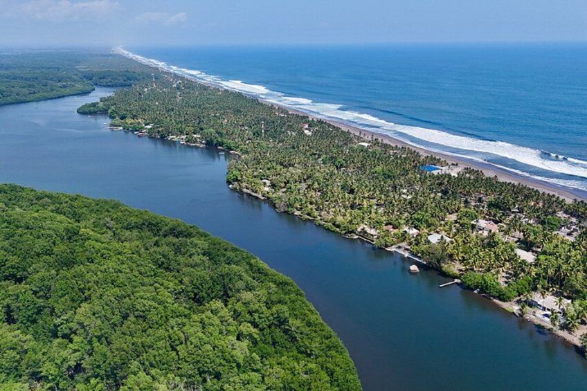 A coastal landscape with a river, dense forest, and a beach. 5