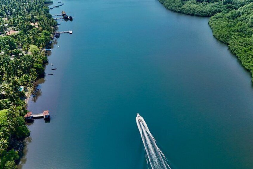 A river with a boat creating a wake, surrounded by dense greenery and docks. 4