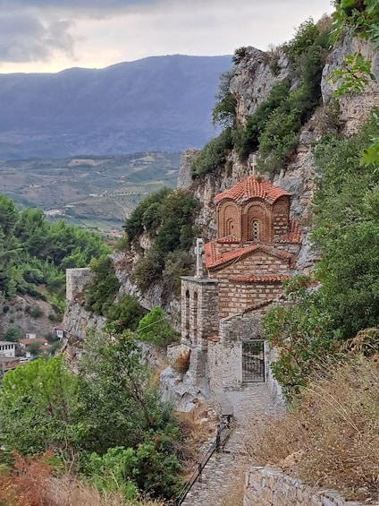 A church built into a cliffside with a stone pathway leading up to it. 2