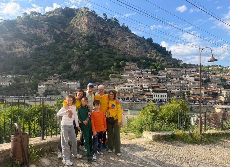 A group of people posing in front of a mountainous town with historic buildings. 4