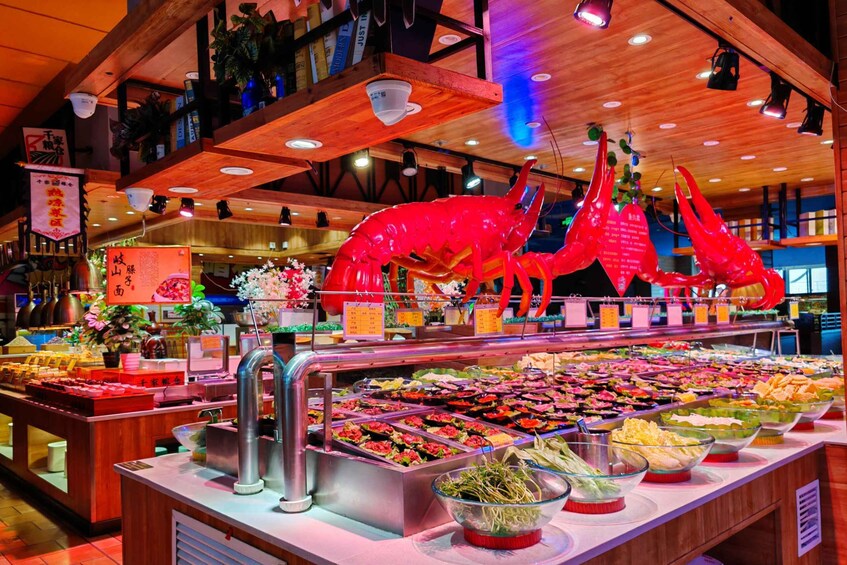 A buffet with various food items and a large red lobster decoration. 2
