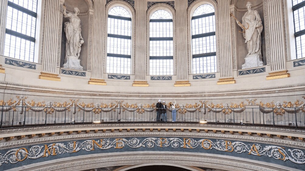 A grand interior with ornate columns, statues, and a decorative balcony. 2