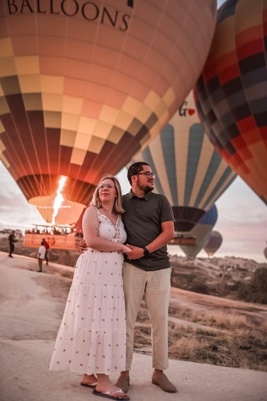 A couple standing in front of a row of hot air balloons with 'BALLOONS' written on one. 4