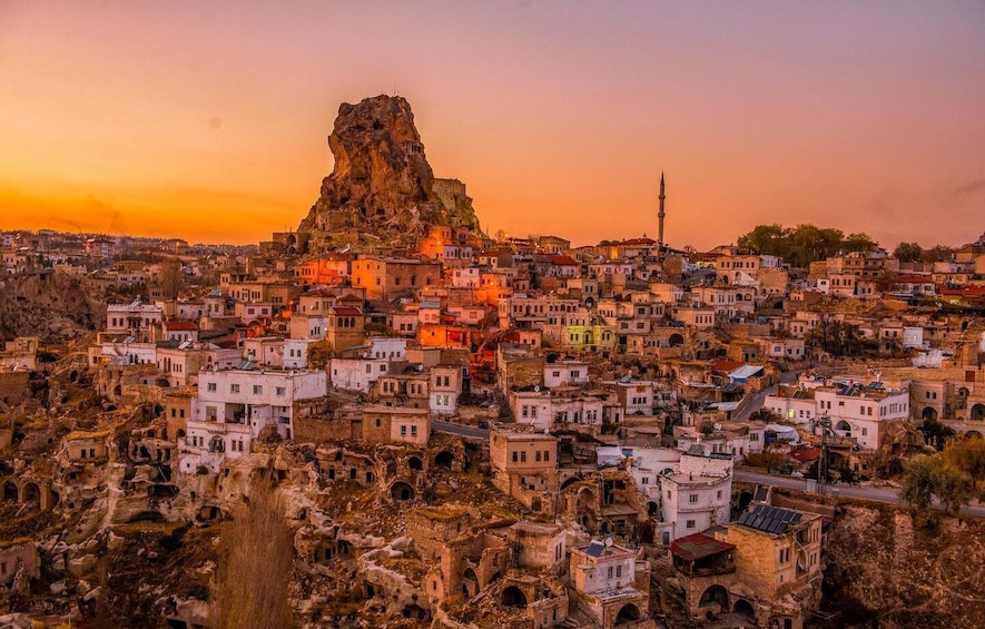 A historic town with a prominent rock formation and a minaret. 1