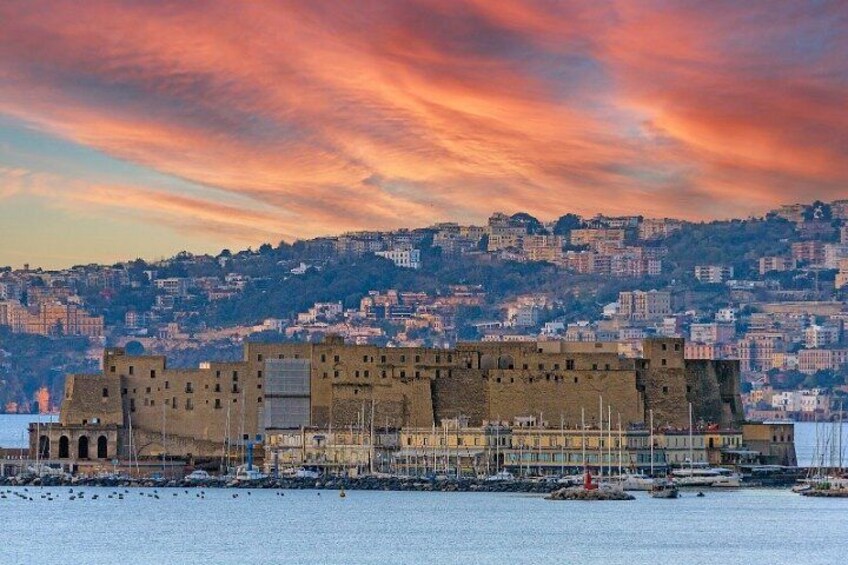 A historic fortress with a waterfront, surrounded by a cityscape with buildings on a hillside. 1