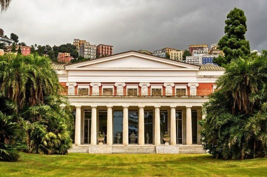 A neoclassical building with columns, surrounded by palm trees and a grassy lawn. 3