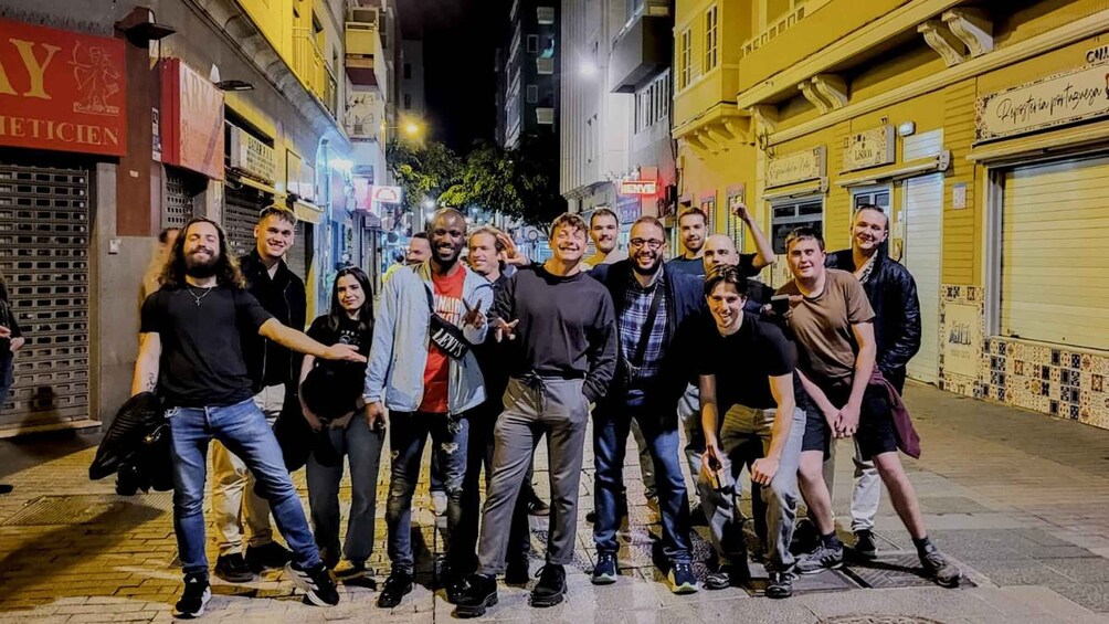 A group of people standing on a city street at night. 1