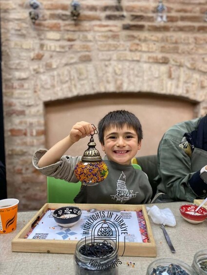 A child holding a colorful lantern, with a brick fireplace in the background. 2