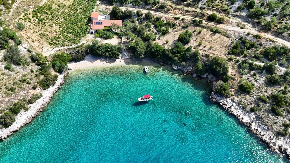 A coastal area with clear turquoise waters, a small boat, and a building surrounded by greenery. 4
