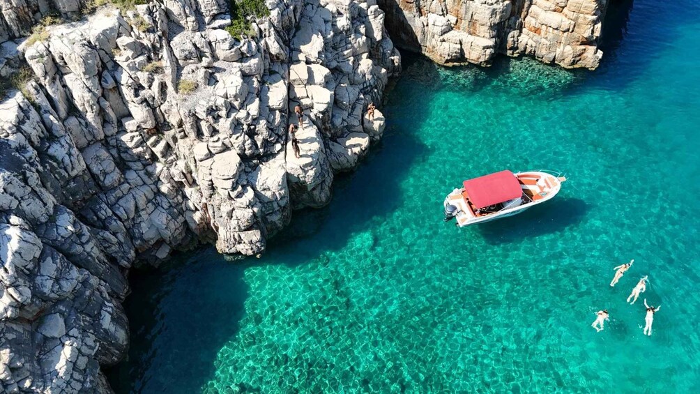 A boat anchored near rocky cliffs with clear turquoise water. 5