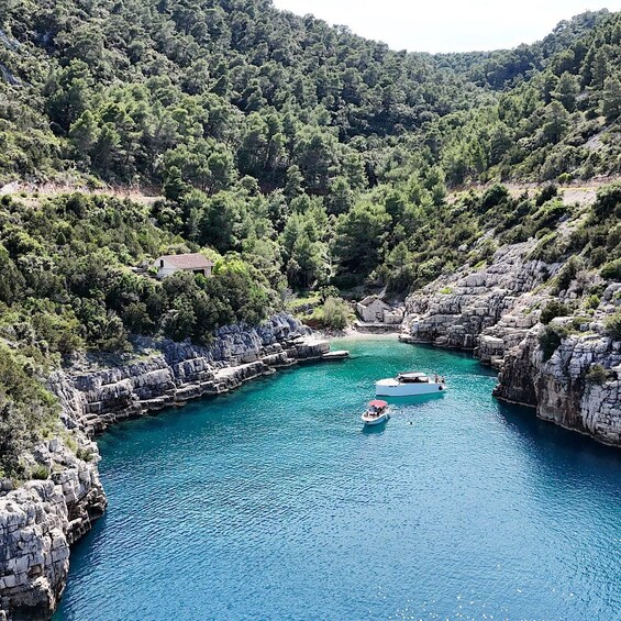 A coastal landscape with rocky cliffs, a turquoise bay, and boats anchored in the water. 2