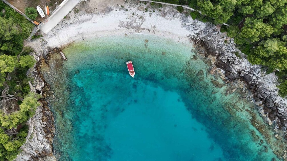 A turquoise lagoon with a boat anchored in the center, surrounded by rocky shores and dense green foliage. 2