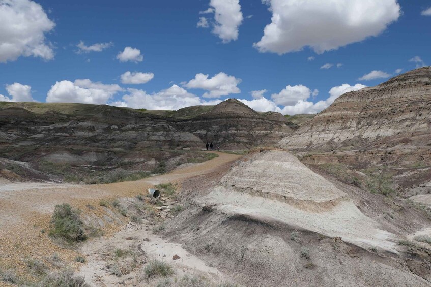A rugged terrain with layered rock formations and a dirt path leading through the landscape. 3