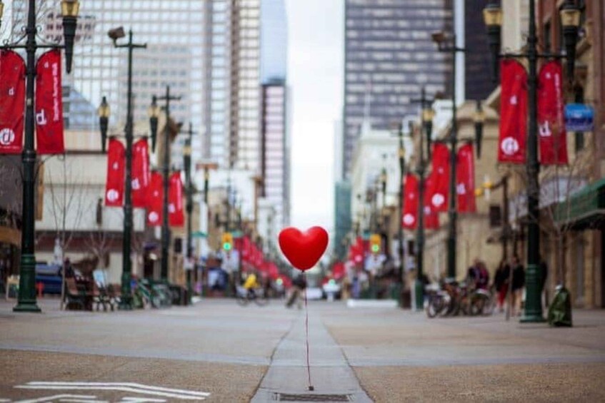 A city street with red flags, a heart-shaped balloon, and tall buildings. 5