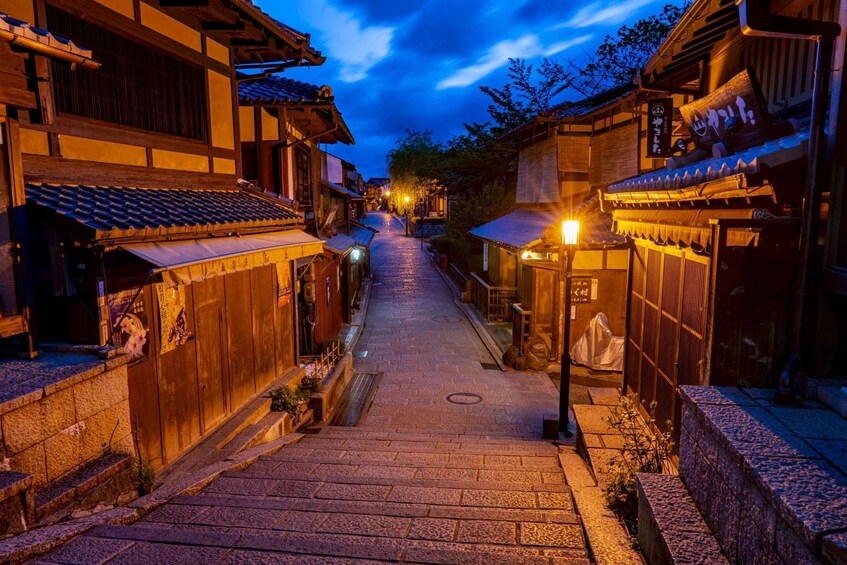 A traditional Japanese street at dusk with wooden buildings and a stone pathway. 2