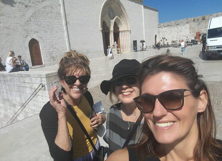 A group of people in front of a historic building with arched doorways and a white facade. 4