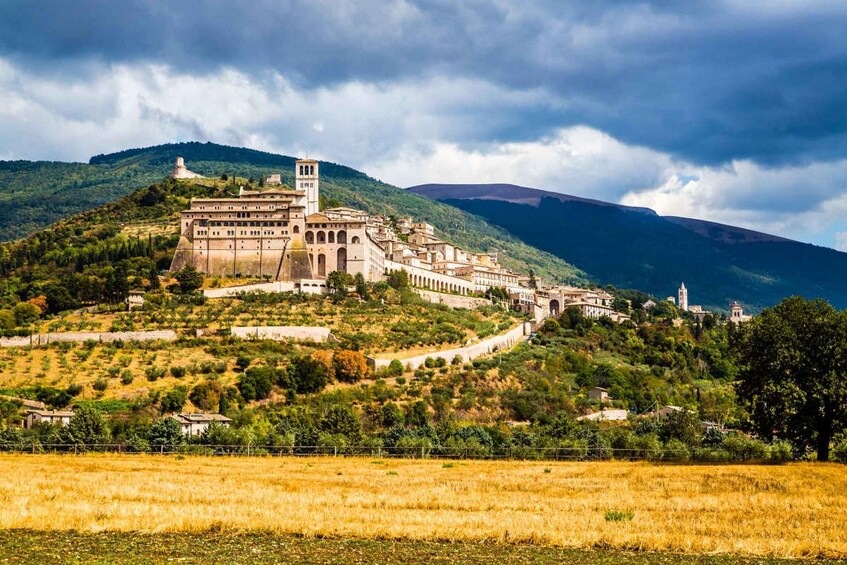 A historic hilltop town with a prominent church and bell tower, surrounded by lush greenery and a mountainous backdrop. 5