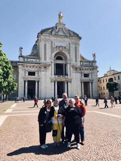 A group of people posing in front of a historic building with a dome and statues. 2