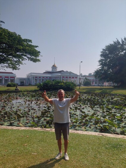 A person standing in front of a pond with lotus flowers, with a building with a golden dome in the background. 2